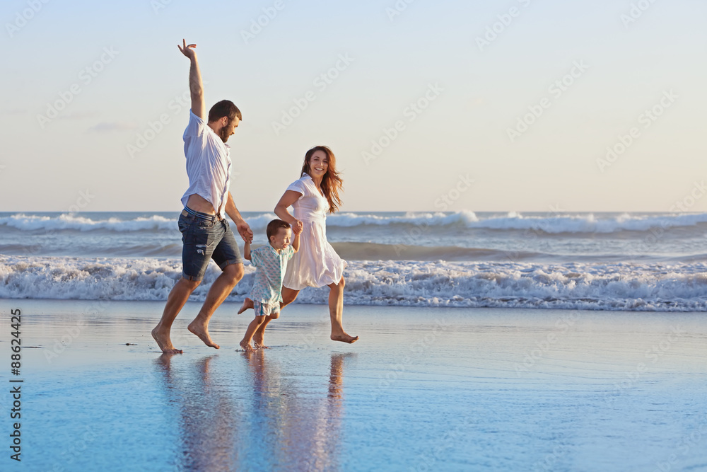 积极的家庭——父亲、带着小儿子的母亲手牵着手，在烟雾中沿着海边尽情奔跑