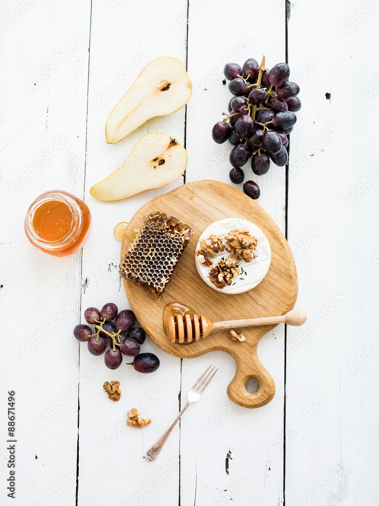 Camembert cheese with grape, walnuts, pear and honey on oak