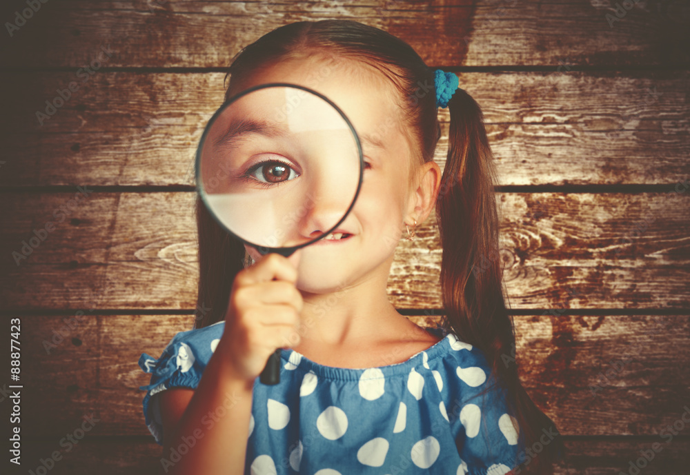 child girl playing with magnifying glass in detective