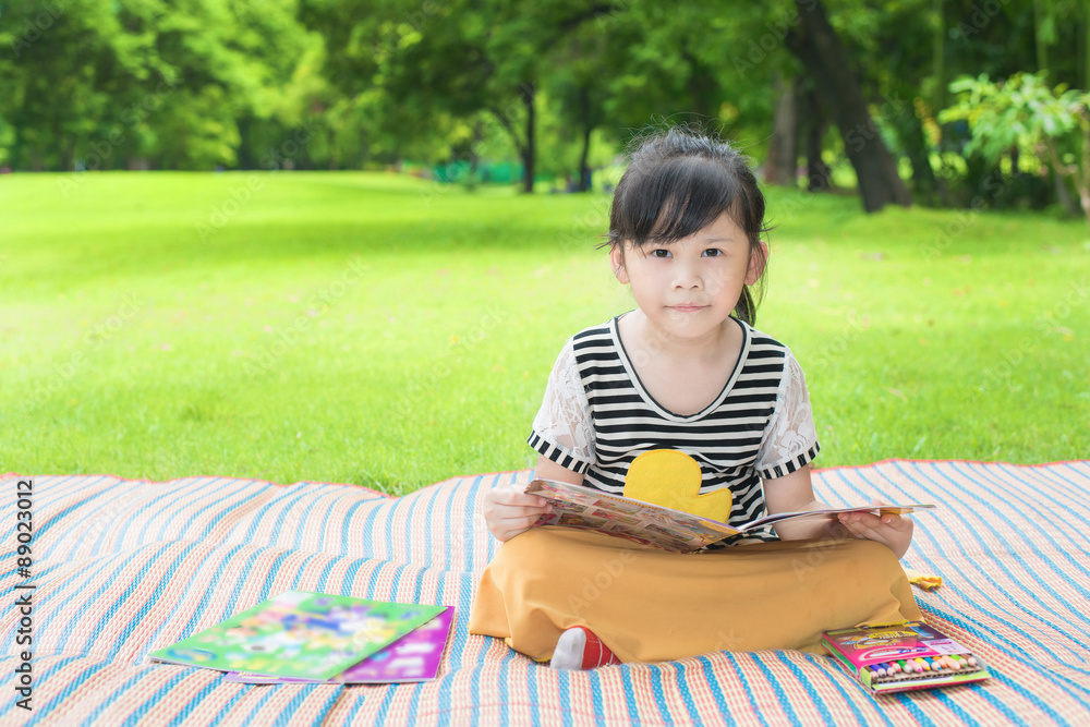 亚洲小女孩在公园看书的肖像