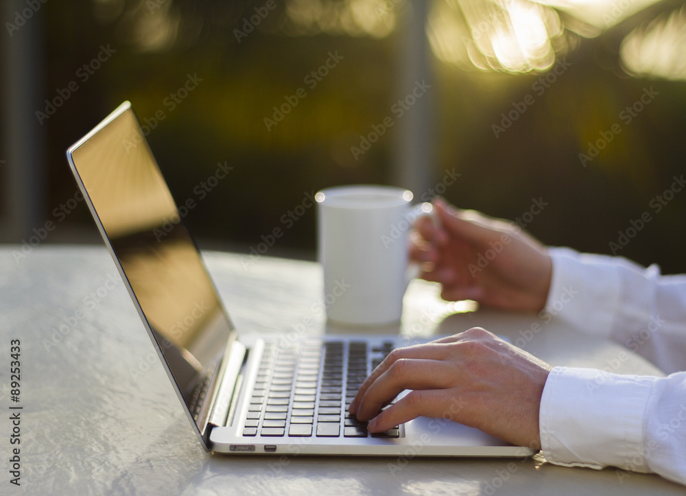 商人在日落时使用笔记本电脑和咖啡