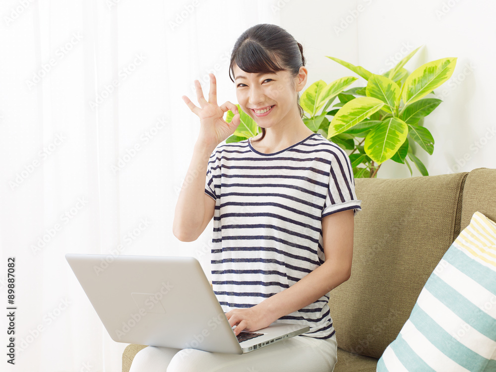 部屋でノートパソコンを使う女性　OKサイン