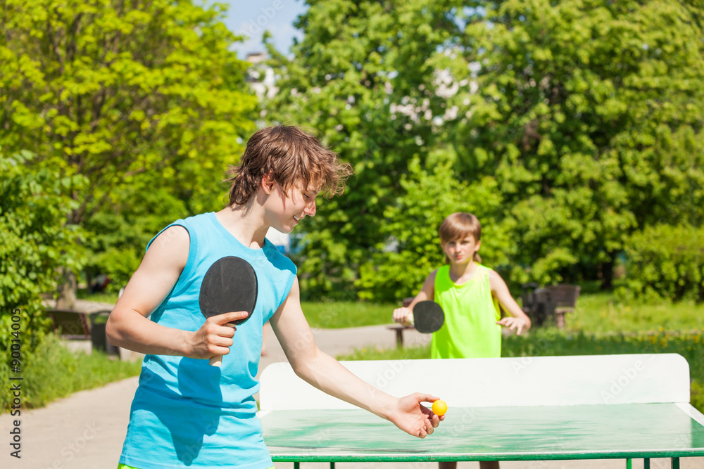 两个男孩在外面一起打乒乓球