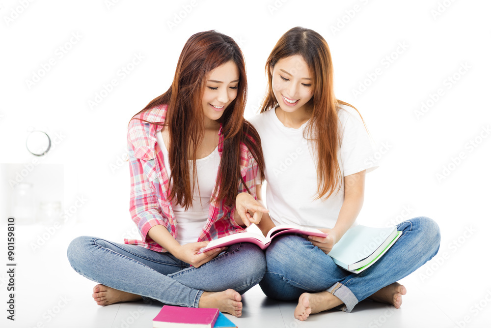两个快乐的十几岁的学生女孩在看书