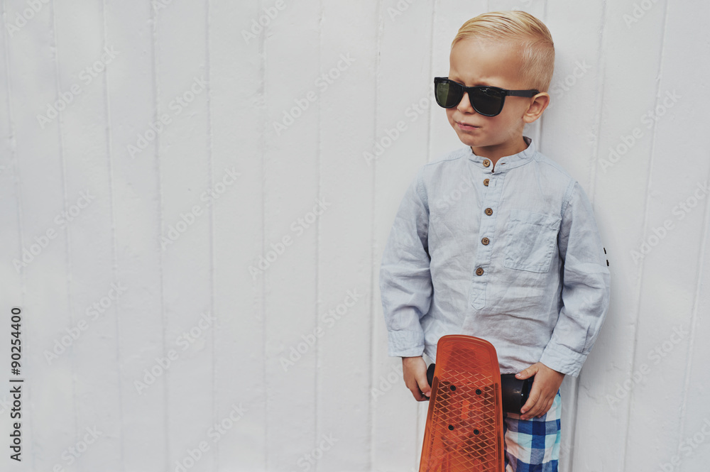 严肃时尚的小男孩与滑板合影