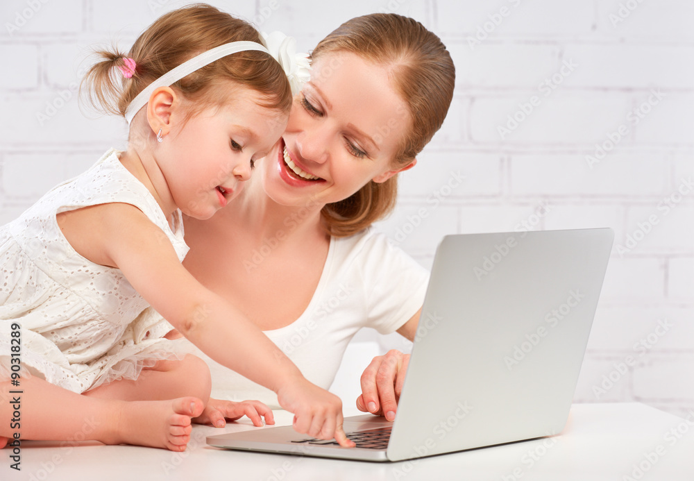 快乐的家庭妈妈和孩子在家里用电脑工作