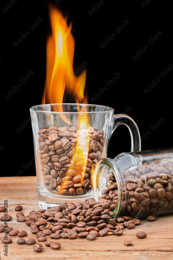 黑色背景下有火焰的杯子里的咖啡豆。