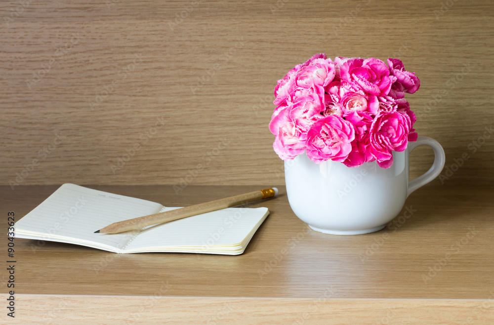带笔记本和铅笔的鲜粉色康乃馨花