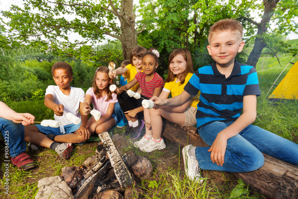 一群孩子拿着棉花糖坐在篝火旁