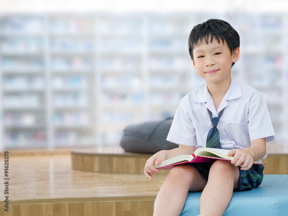穿着制服的亚洲男生在学校图书馆看书
