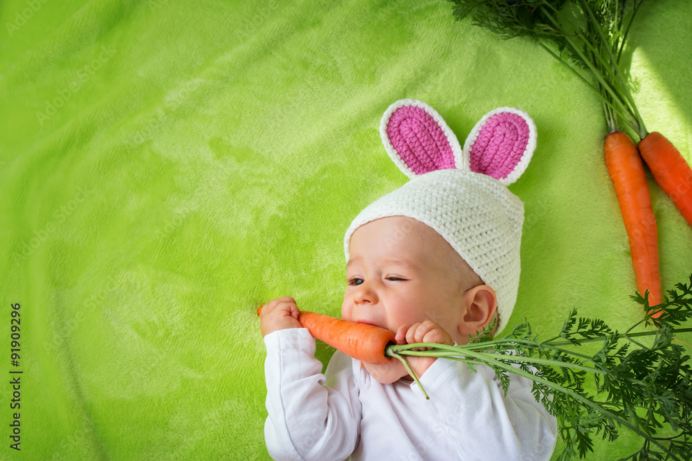 戴着兔子帽的婴儿吃胡萝卜