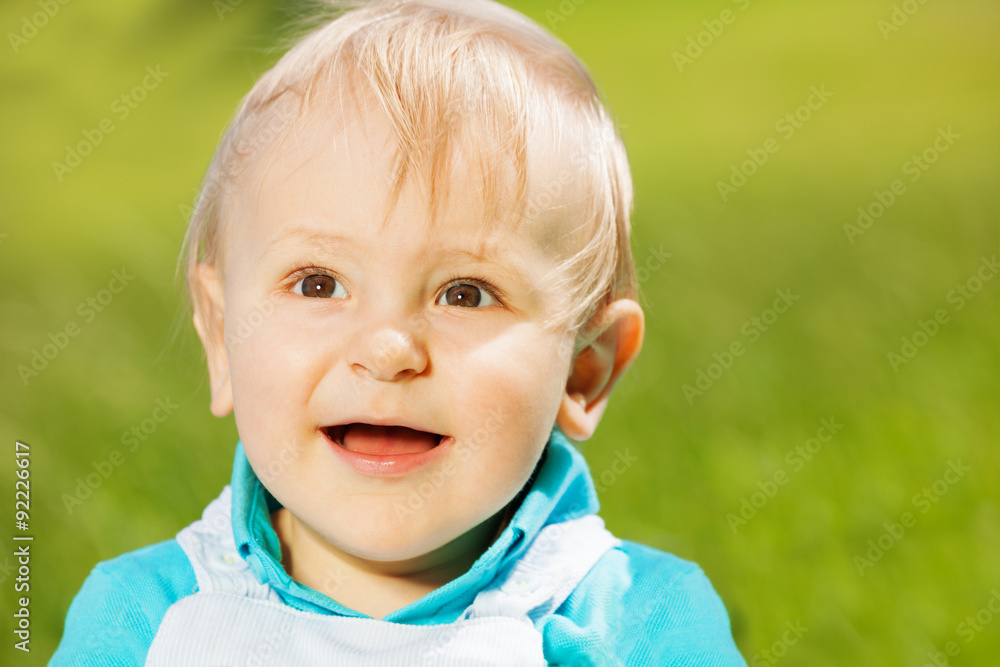 绿草上微笑的蹒跚学步的孩子的肖像