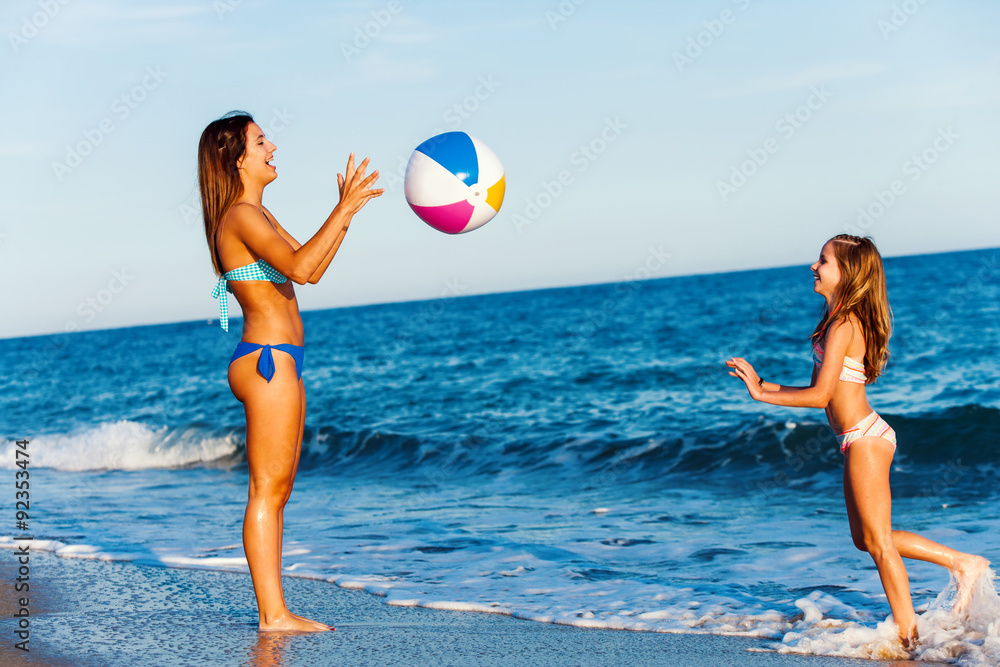Young girls playing with inflatable plastic ball on beach.