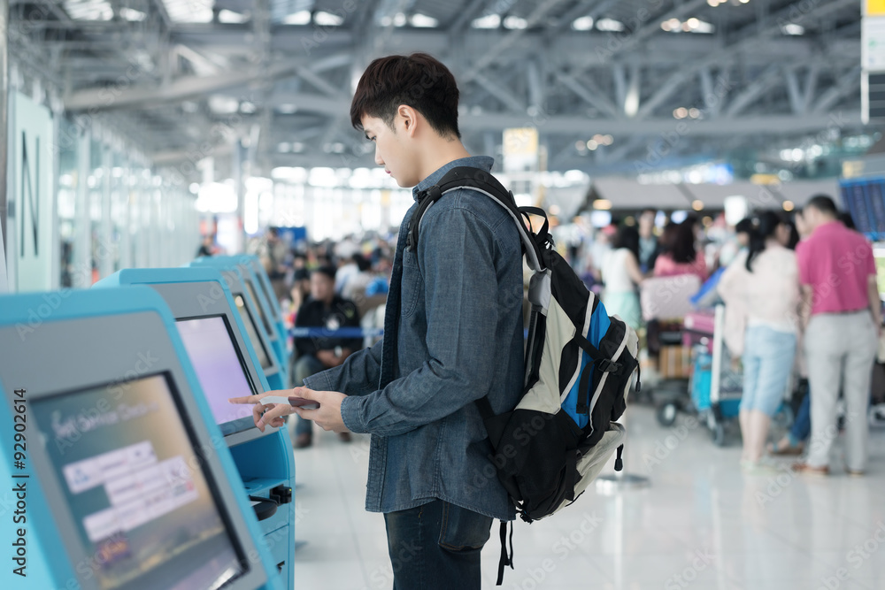 一名亚洲年轻男子在机场使用自助值机柜台