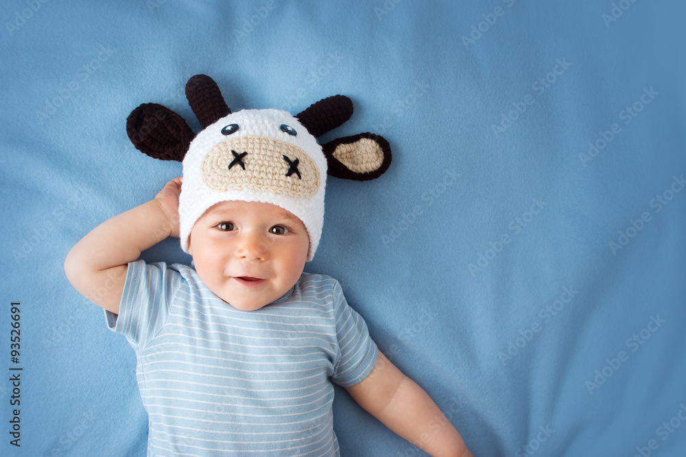 蓝色毯子上戴着奶牛帽的婴儿