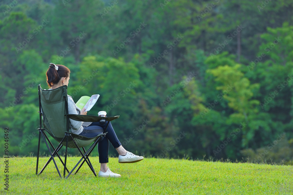 年轻女子坐在露营椅上在公园看书