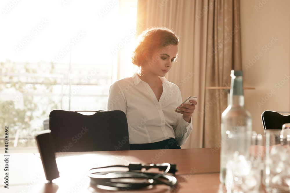 Businesswoman at conference table using mobile phone