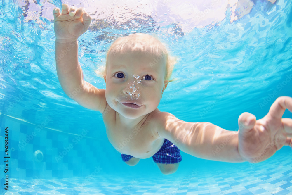 小男婴在游泳池里有趣地在水下游泳和潜水的有趣头像。积极治疗