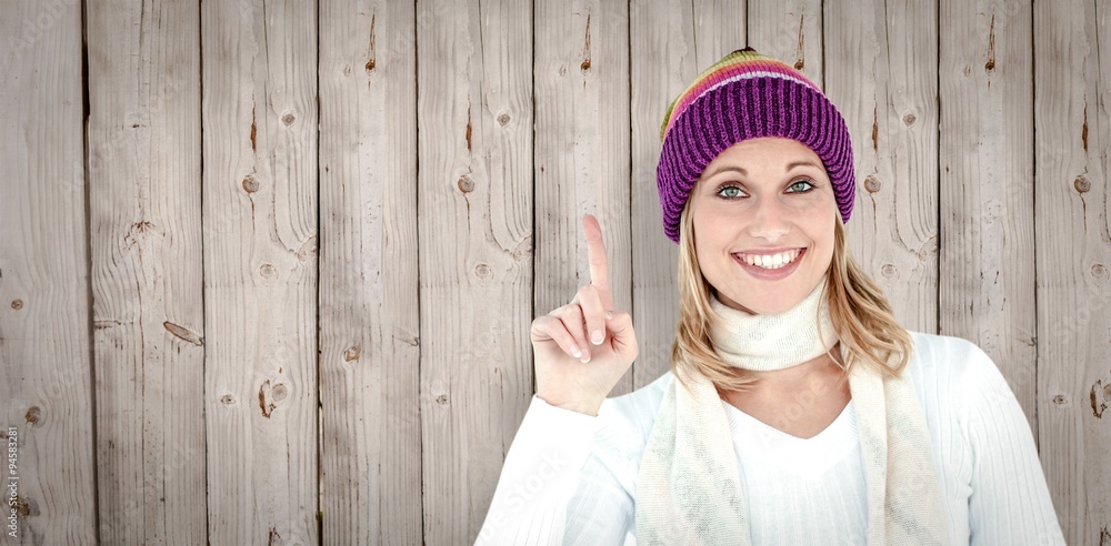 Composite image of joyful woman with a colorful hat pointing up