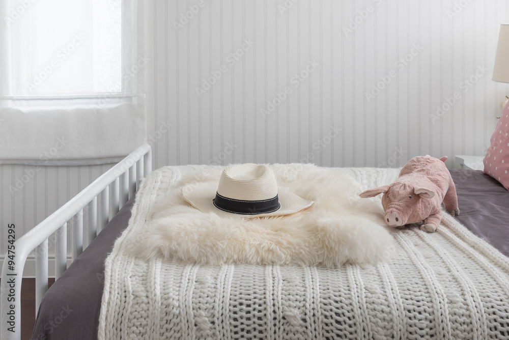 白色木床上的粉色玩偶和经典帽子