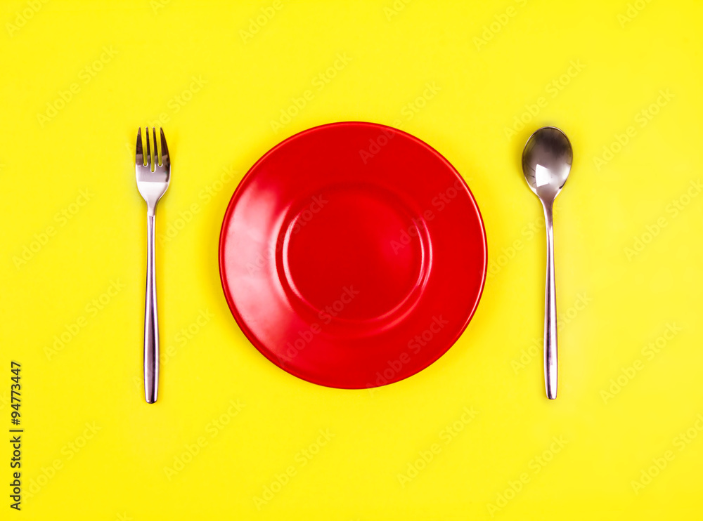 带勺子和叉子的空红盘子俯视图