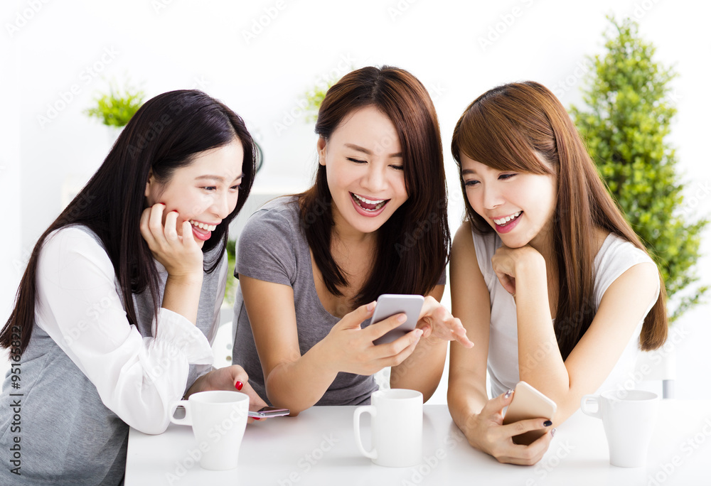  happy young women watching smart phone  in living room