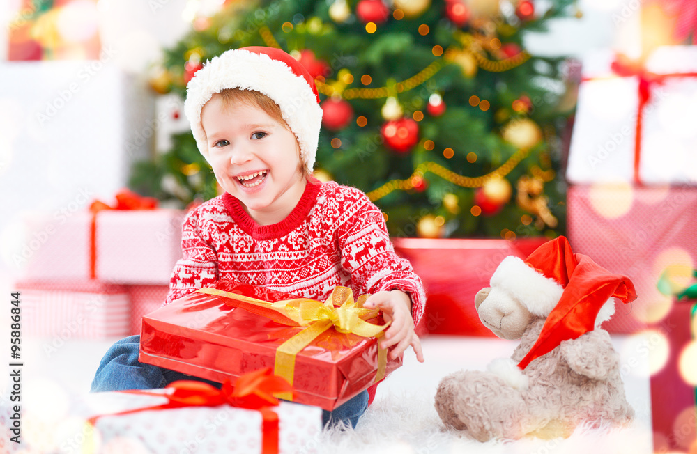 圣诞树旁带着圣诞礼物的快乐孩子