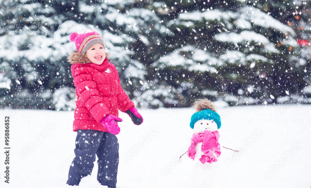 快乐的小女孩和雪人在冬天散步