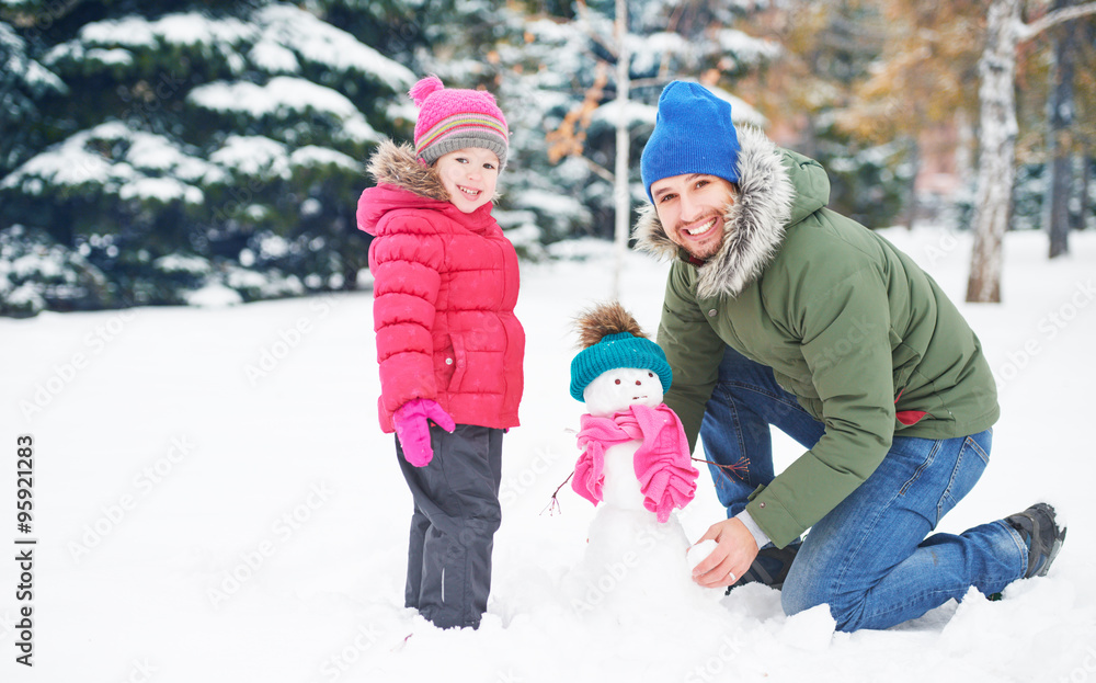 快乐家庭父亲和小女孩在冬天堆雪人