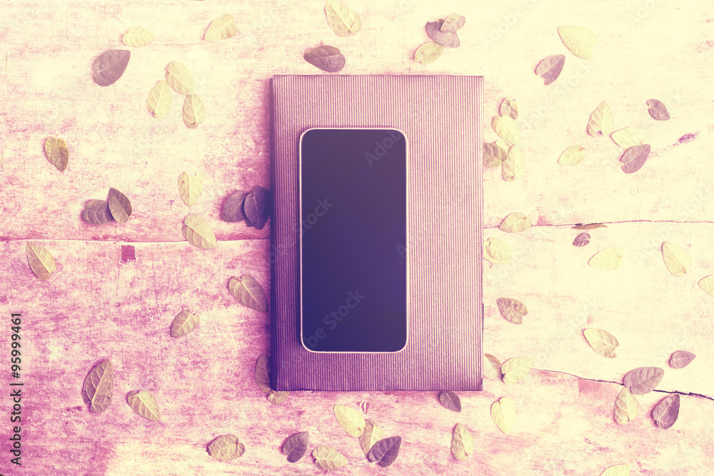 空白智能手机屏幕，木桌上有日记和树叶