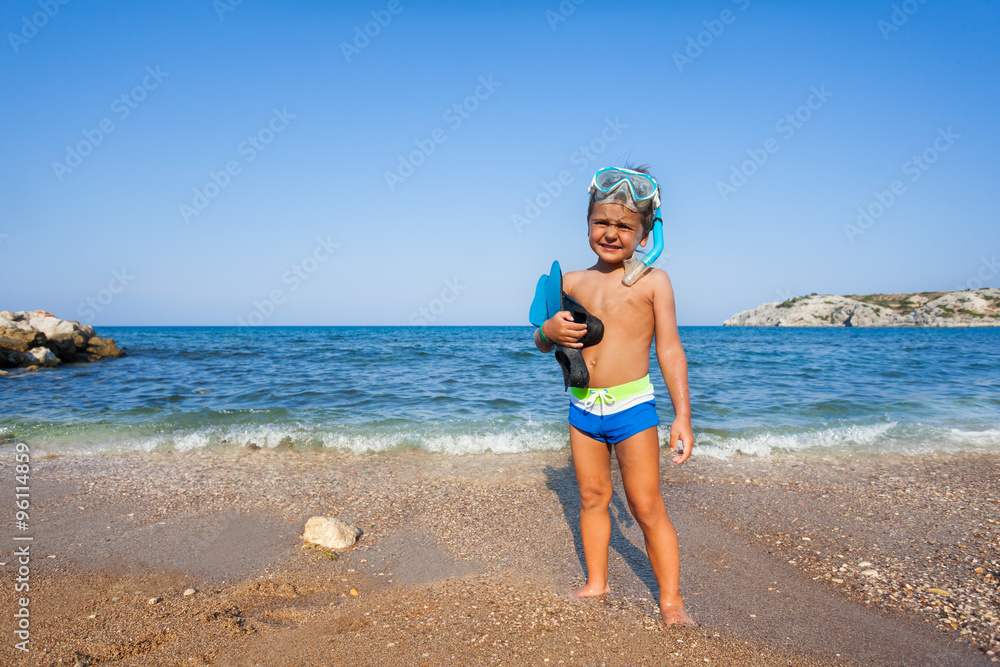 戴着口罩、划桨的男孩站在海边
