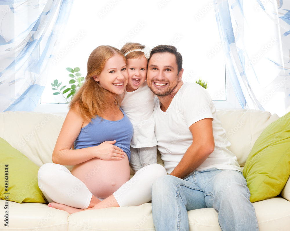 幸福的家庭。怀孕的母亲、父亲和孩子的女儿在家