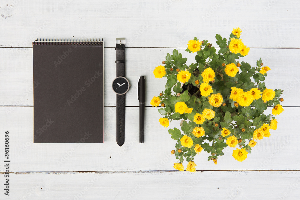 木桌上的记事本、手表、钢笔和花瓶
