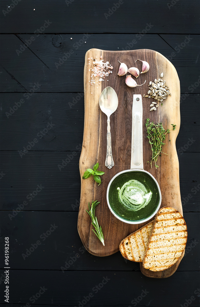 自制的金属勺绿色菠菜奶油汤，配烤面包片、香草和香料