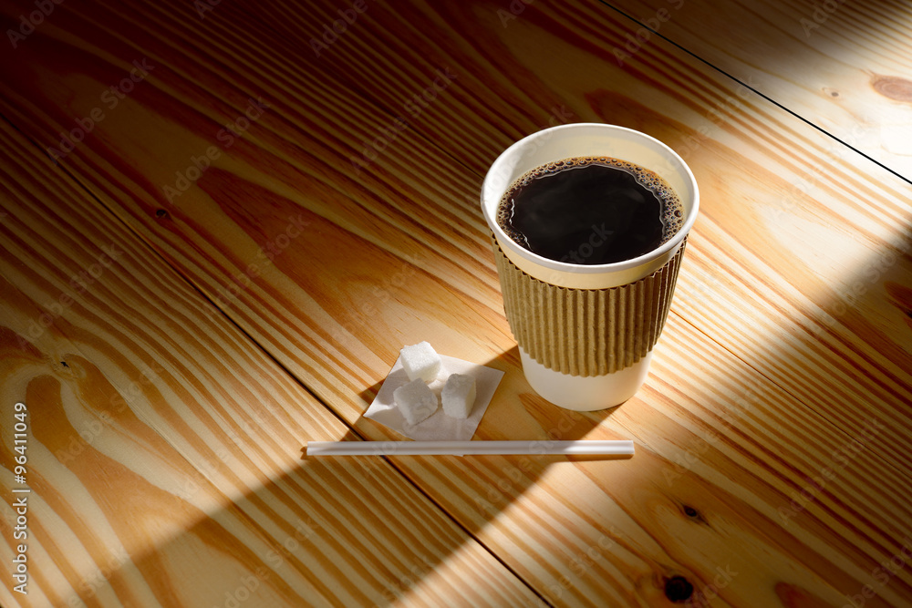 木制背景上的晨曦中的纸杯咖啡