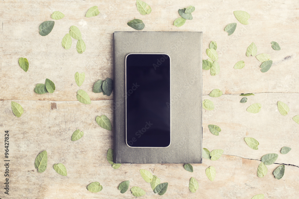 Blank black smartphone with diary on wooden table with leaves, m