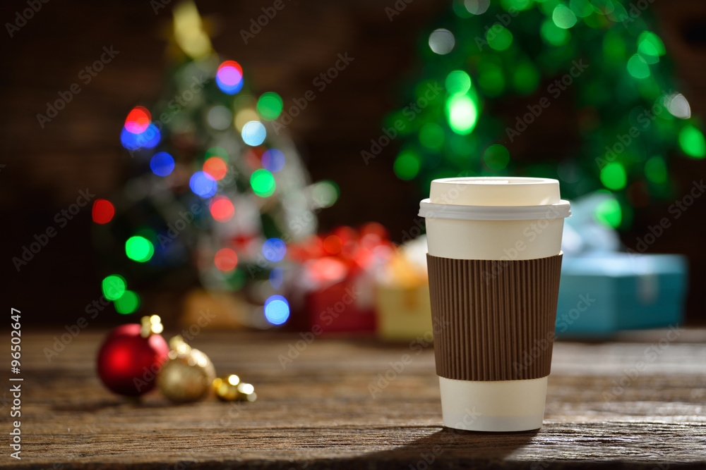 一杯烟雾弥漫的纸杯咖啡，周围是圣诞彩灯上的圣诞装饰品bokeh backgro