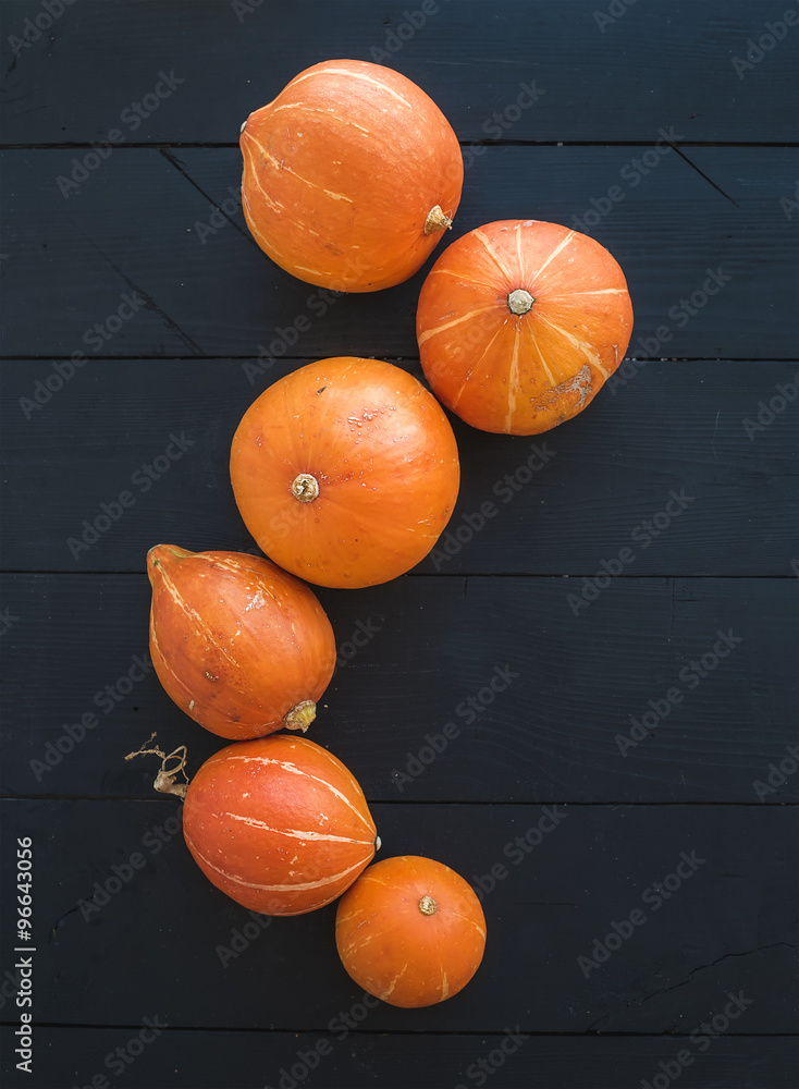 Ripe pumpkins over black rustic wooden backdrop, top view