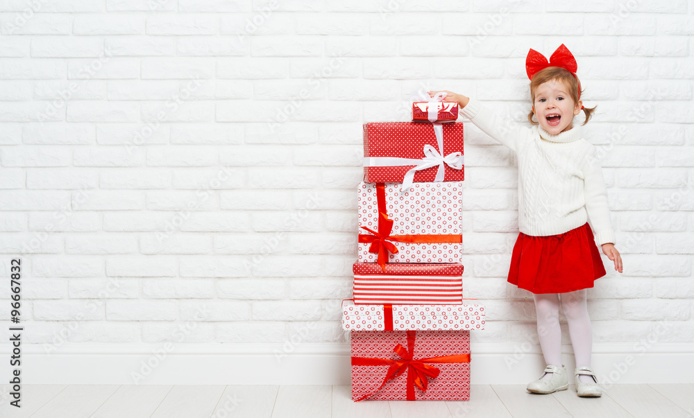 happy little girl child with Christmas gifts at wall
