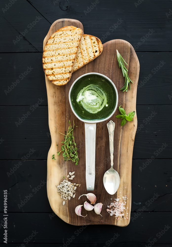 自制的金属勺绿色菠菜奶油汤，配烤面包片、香草和香料