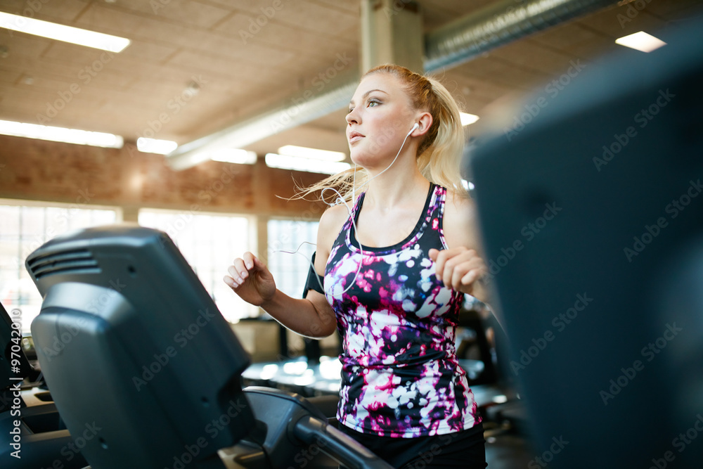 年轻女性在健身俱乐部的跑步机上跑步
