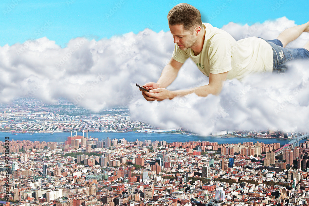 一名男子拿着智能手机躺在大都市上空的云层上