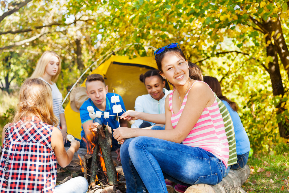 快乐的青少年坐在露营地上拿着棉花糖