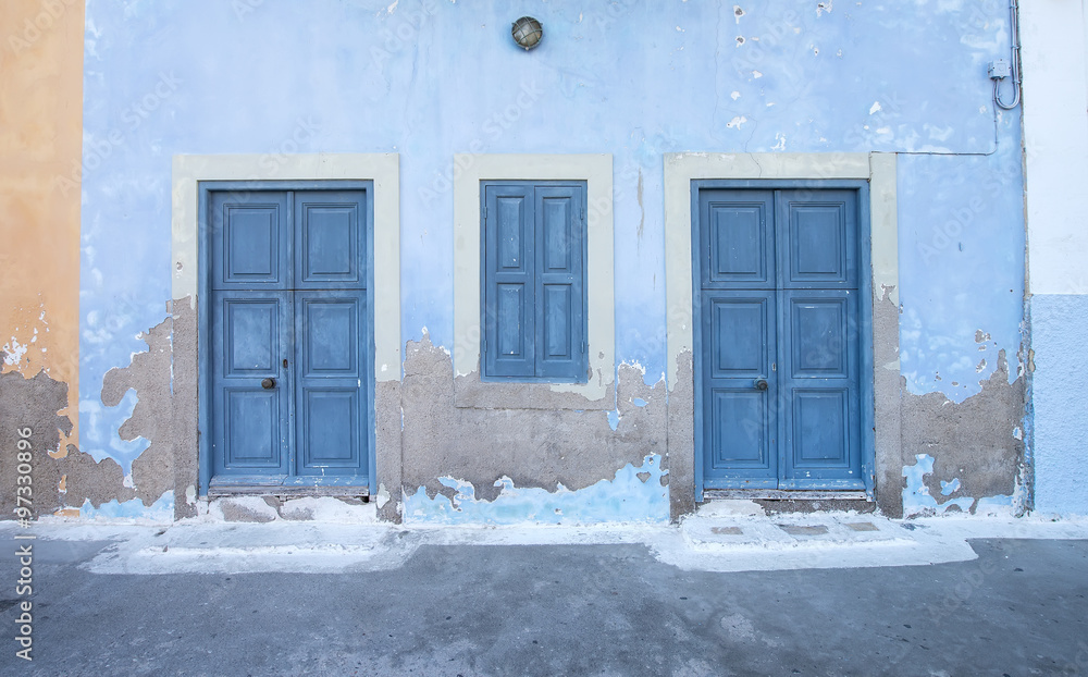 地中海风格的外部。蓝色木门和百叶窗，希腊岛上的旧漆墙