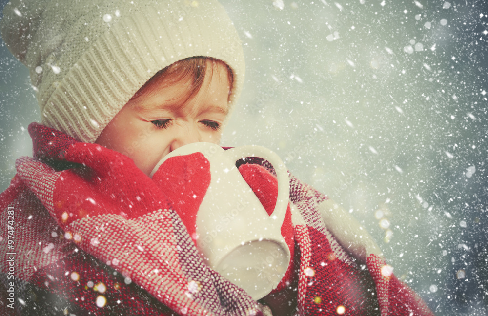 在寒冷的冬天，在户外喝一杯热饮，快乐的小女孩
