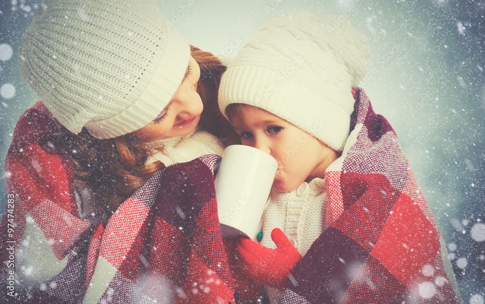 幸福家庭母亲和孩子在冬季散步时喝热茶