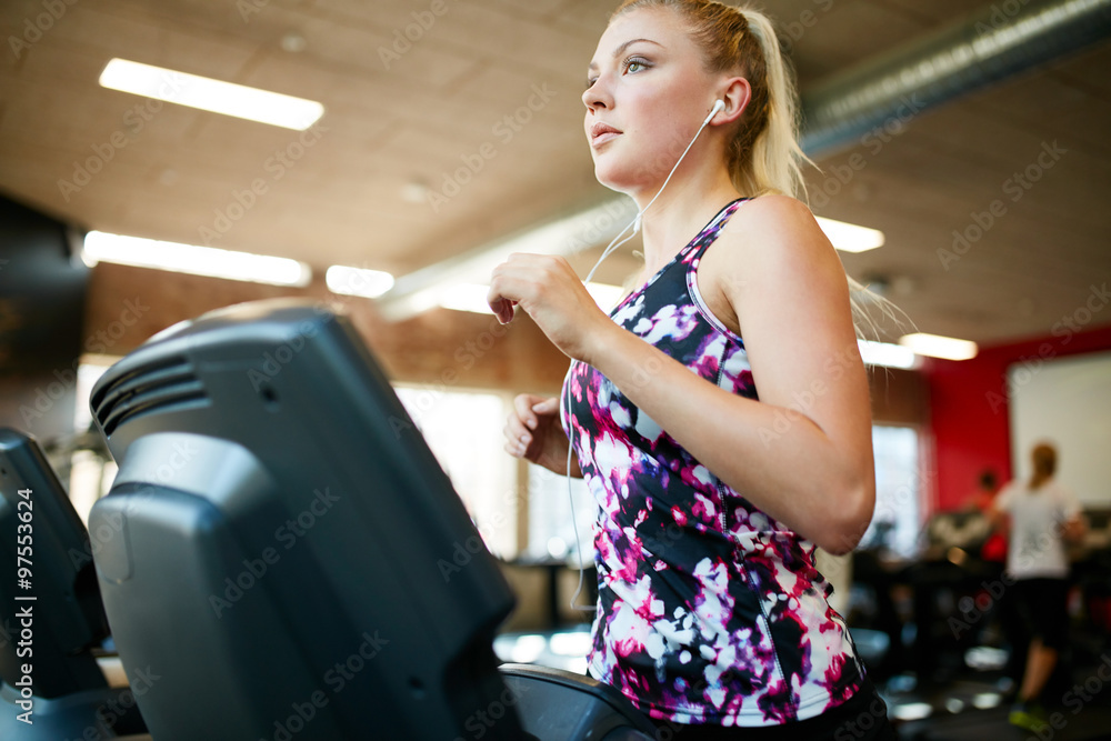 健身女性在健身房跑步机上跑步