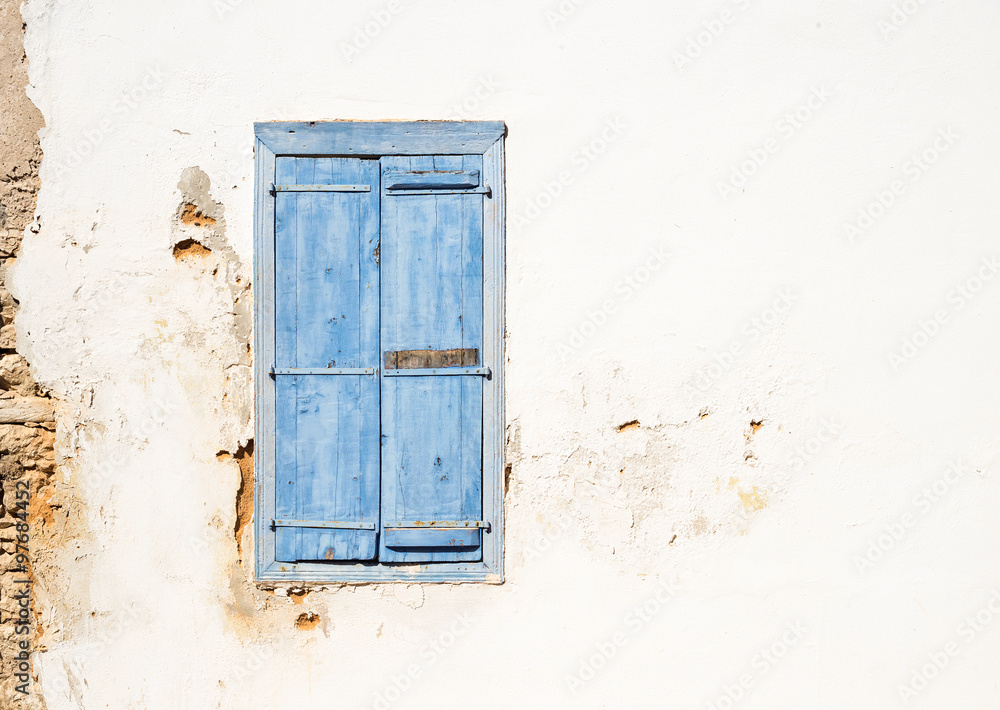 Mediterranean style old window. Blue on light wall with closed shutters