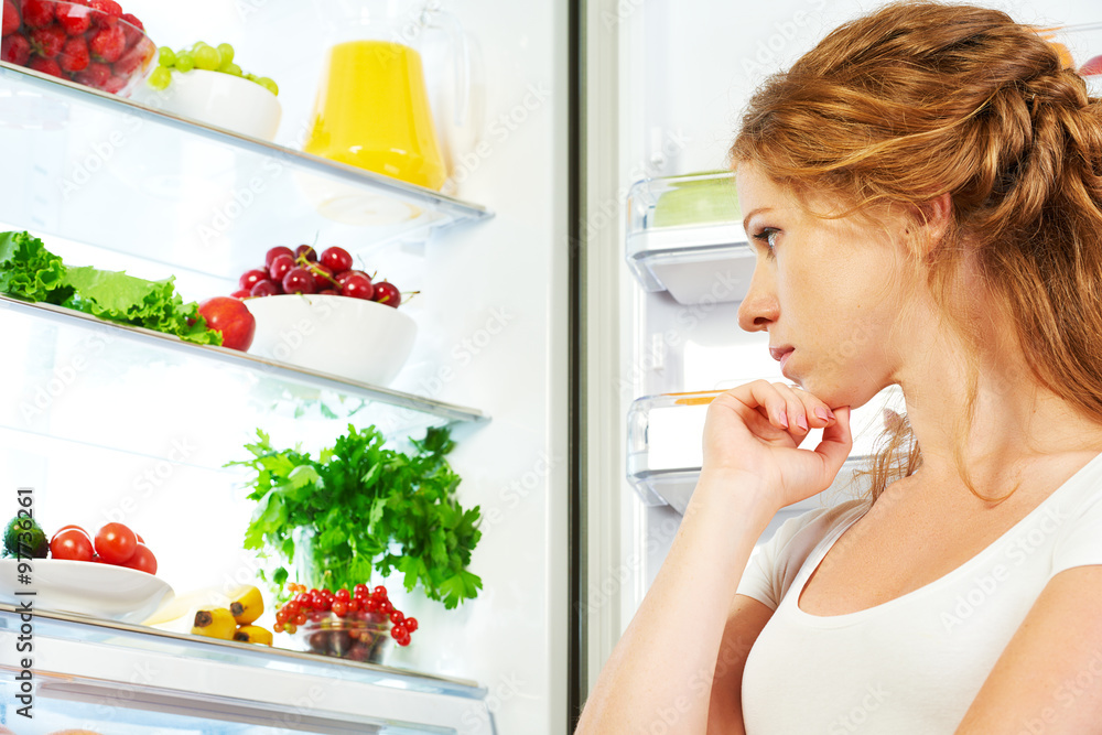 快乐的女人和打开的冰箱里有水果、蔬菜和他