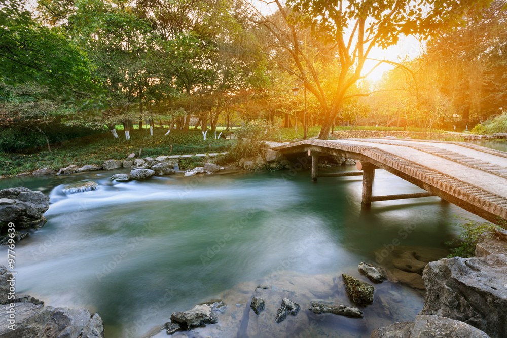 日落中的中国花园里的小溪和小桥